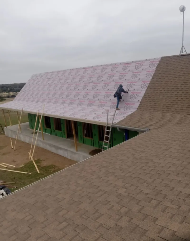 Worker preparing underlayment for a metal roof installation in Mission Bend